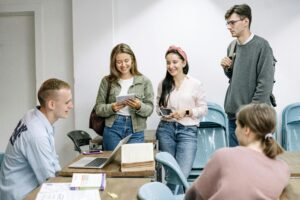 students talking to a teacher at a laptop after class