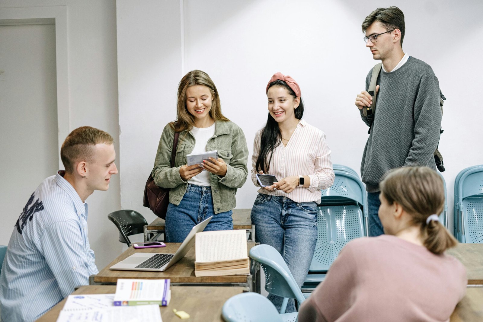 students talking to a teacher at a laptop after class